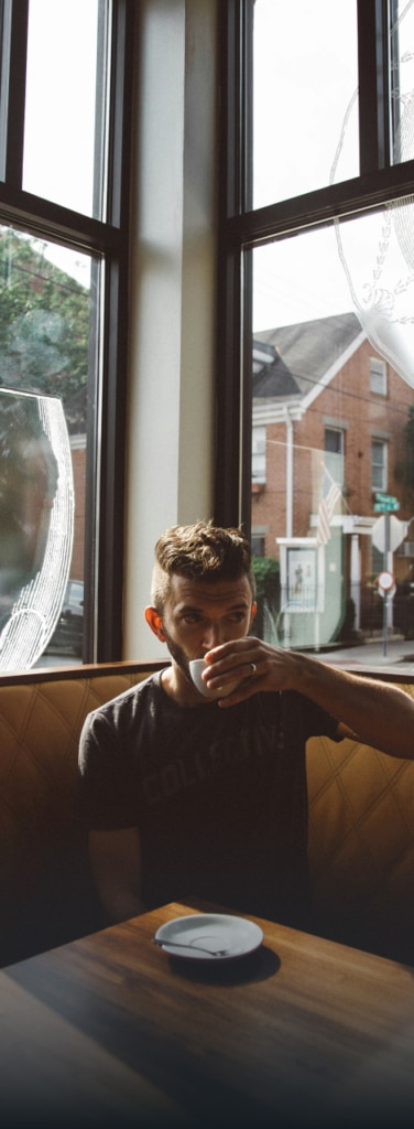 a man drinking coffee at a corner booth