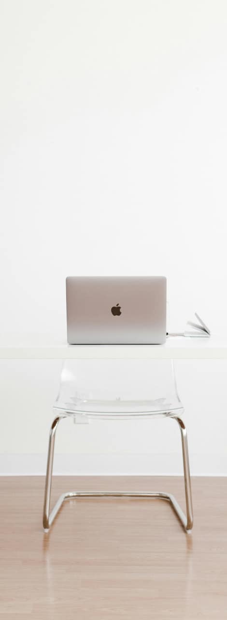 A ghost desk and chair with a laptop open sitting on top