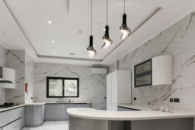 modern kitchen with stone tile walls and three pendant lights